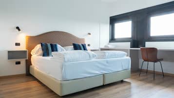 Habitación de hotel moderna con una cama grande, un escritorio y una ventana con persianas.