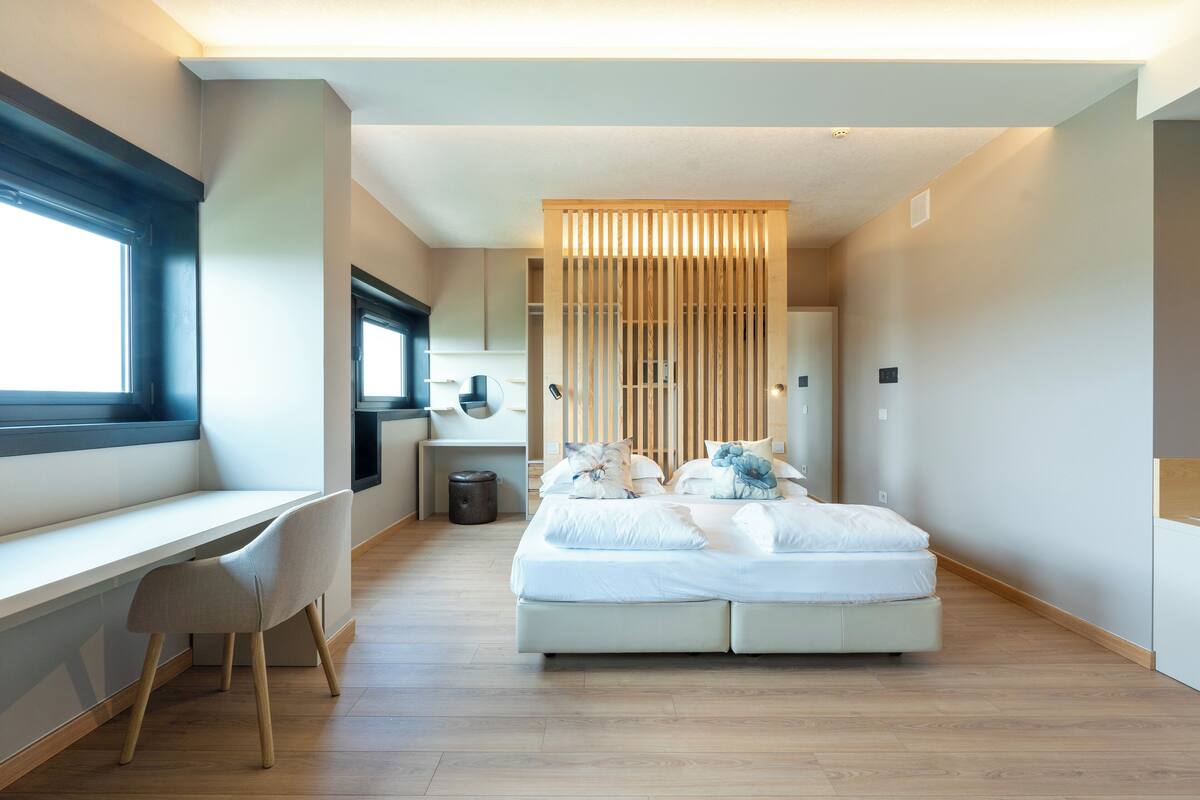 A modern bedroom with a bed, a desk, and a chair.