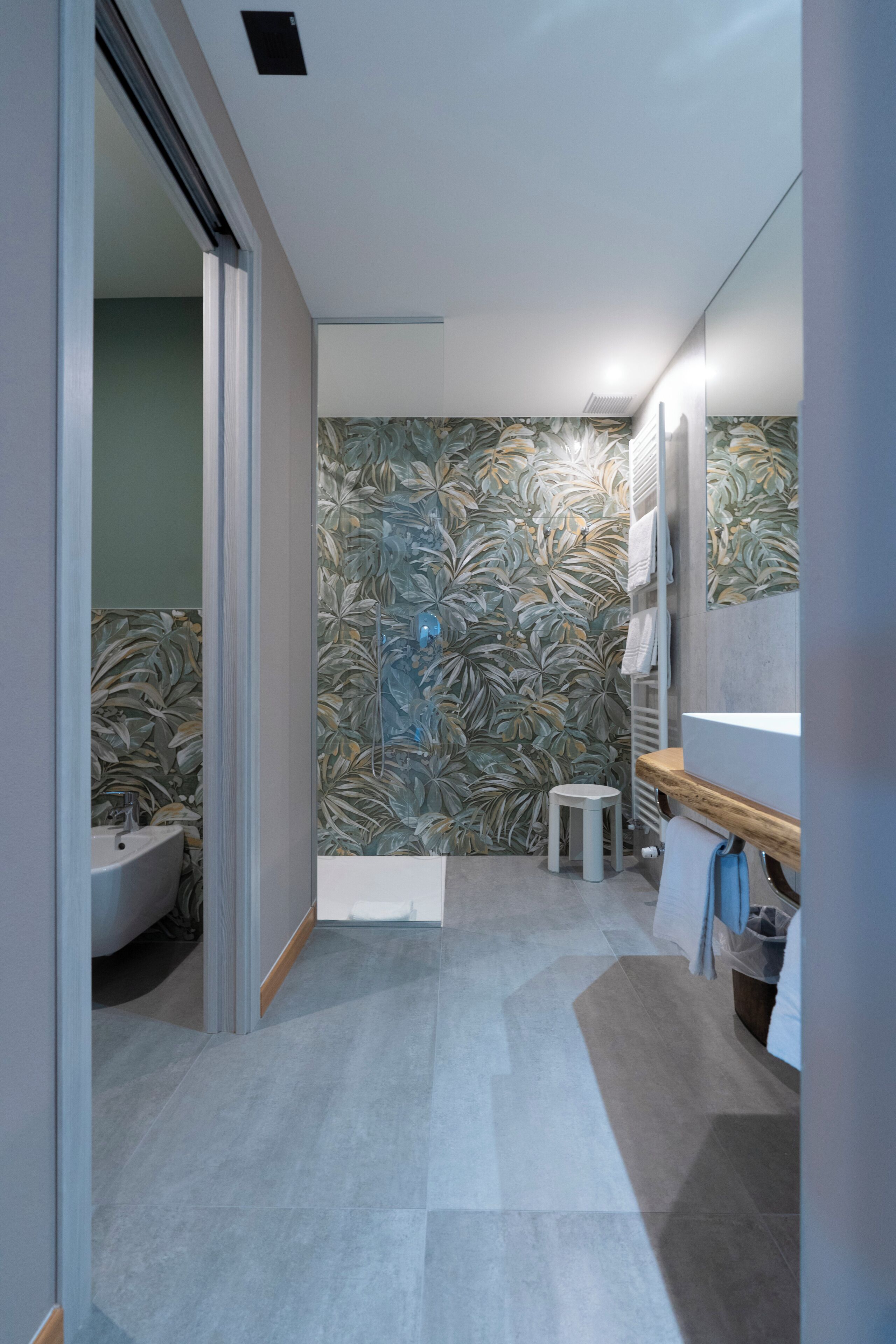 A modern bathroom with a large mirror, a sink, and a toilet.
