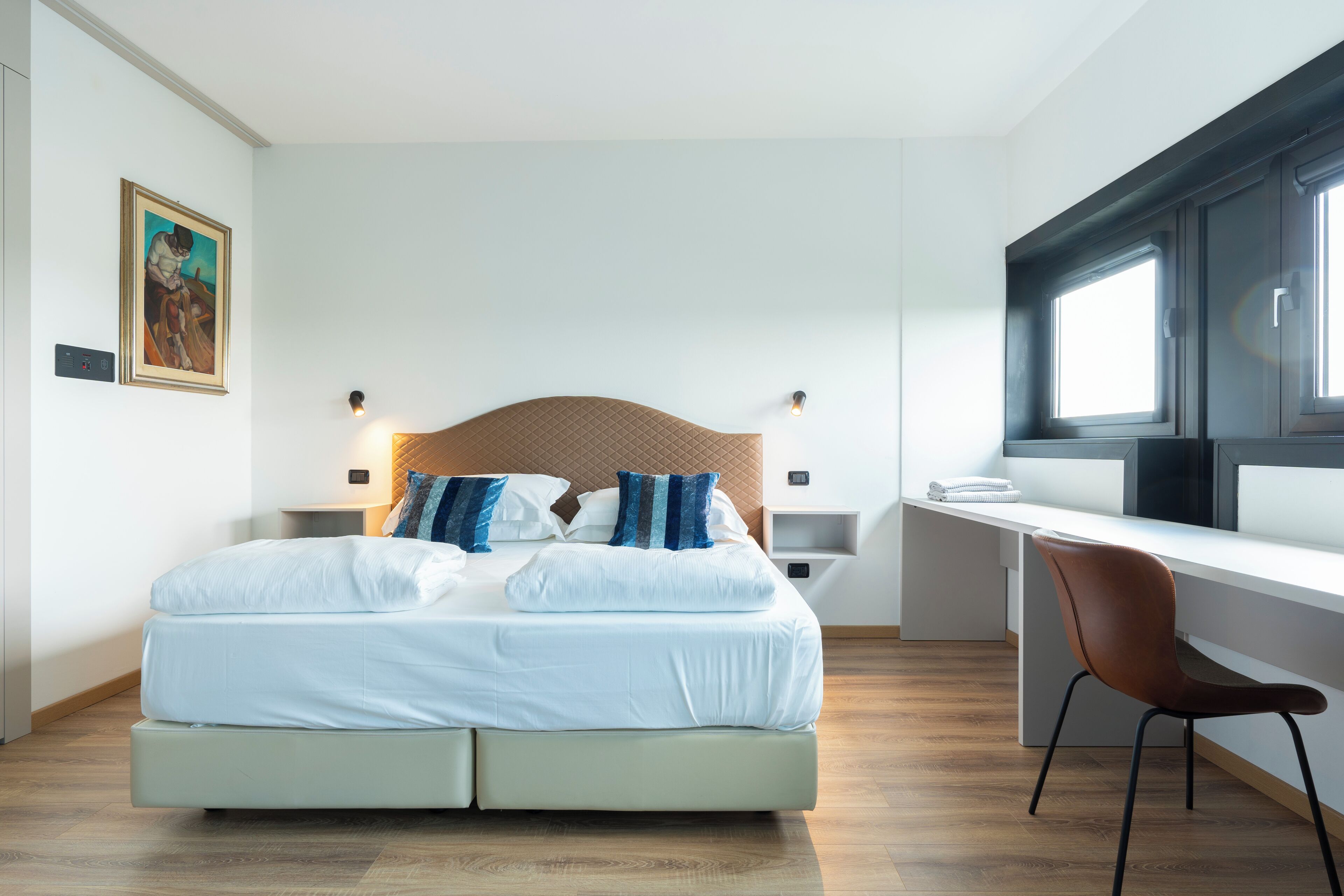 Une chambre à coucher moderne avec un lit, des tables de chevet, un bureau et une chaise.
