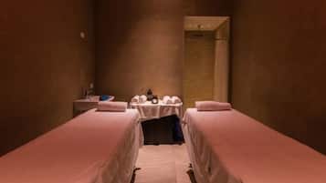 Een hotelkamer met twee éénpersoonsbedden, een tafeltje met handdoeken en een telefoon, en een douche.
