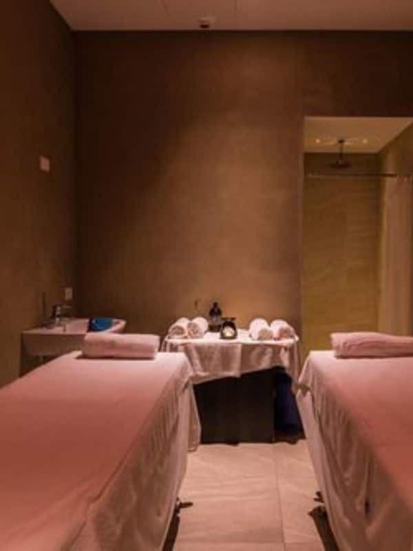 Two single beds with crisp linens and pillows, a large mirror, and a small table with a lamp.