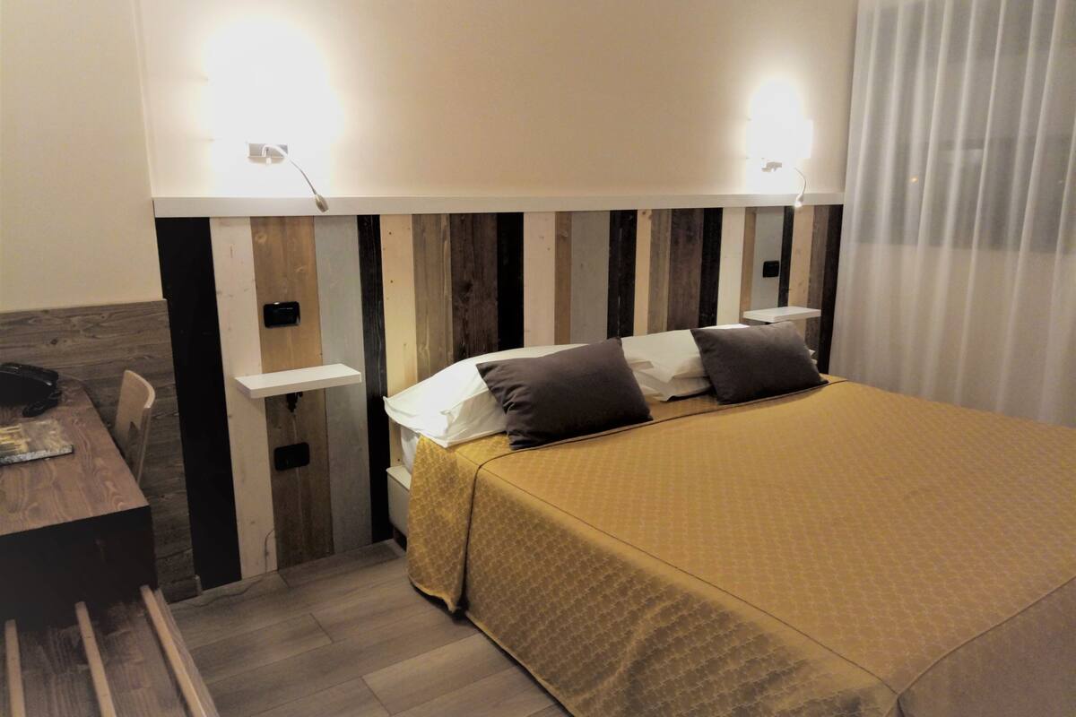 A hotel room with a bed, bedside table, and a chair.