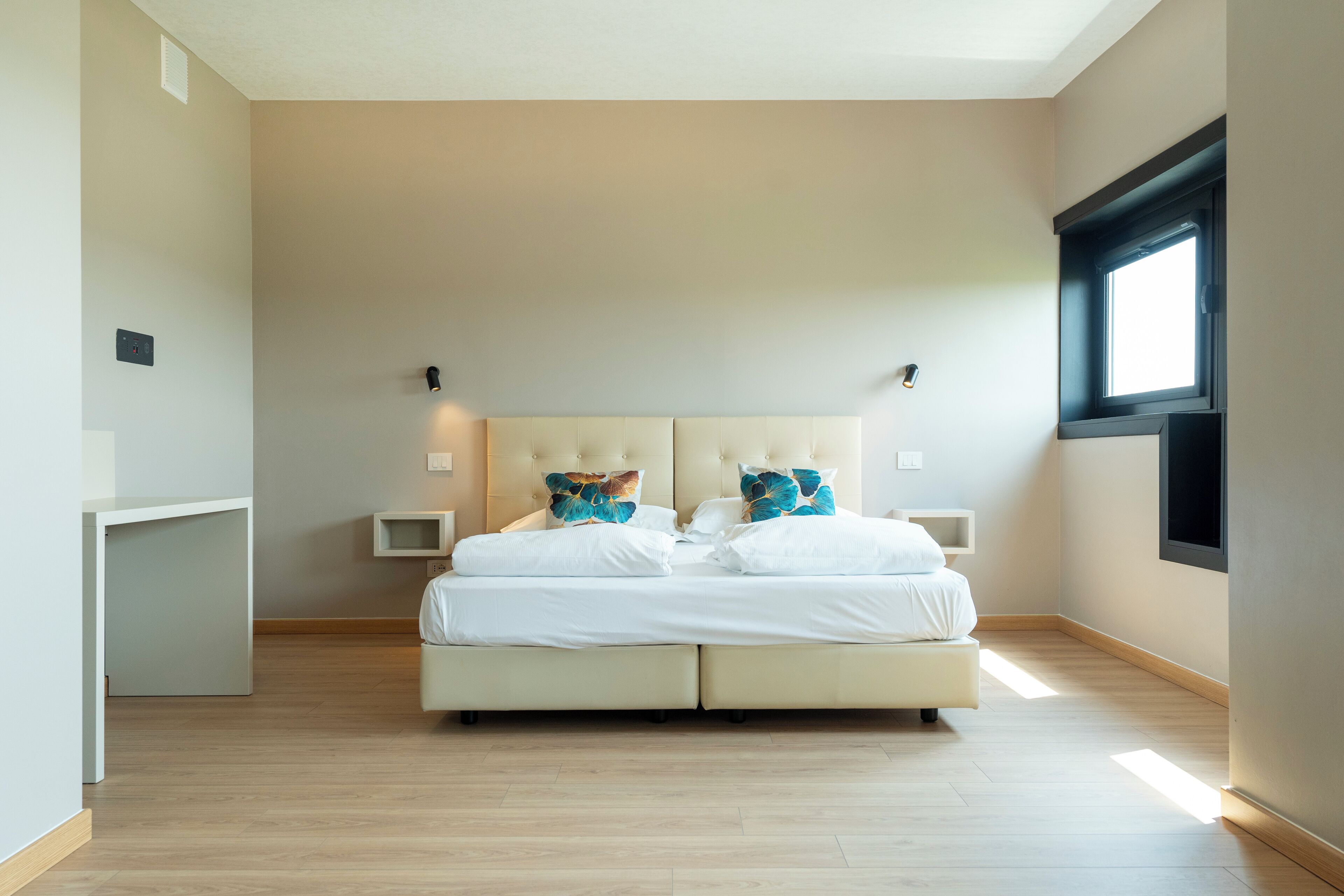 Ein Schlafzimmer mit einem großen Bett, zwei Nachttischen und einem Fenster.