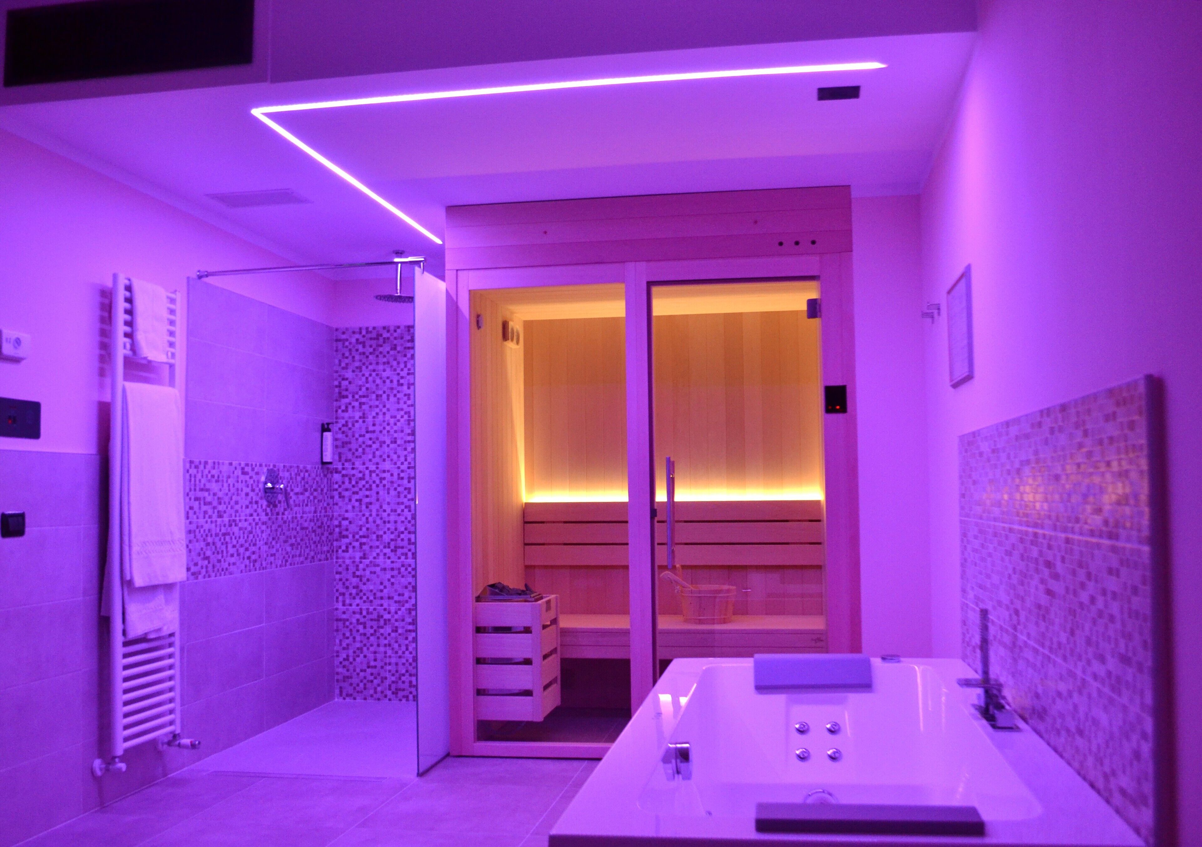 A modern bathroom with a glass-enclosed shower, a white bathtub, and a wooden vanity.