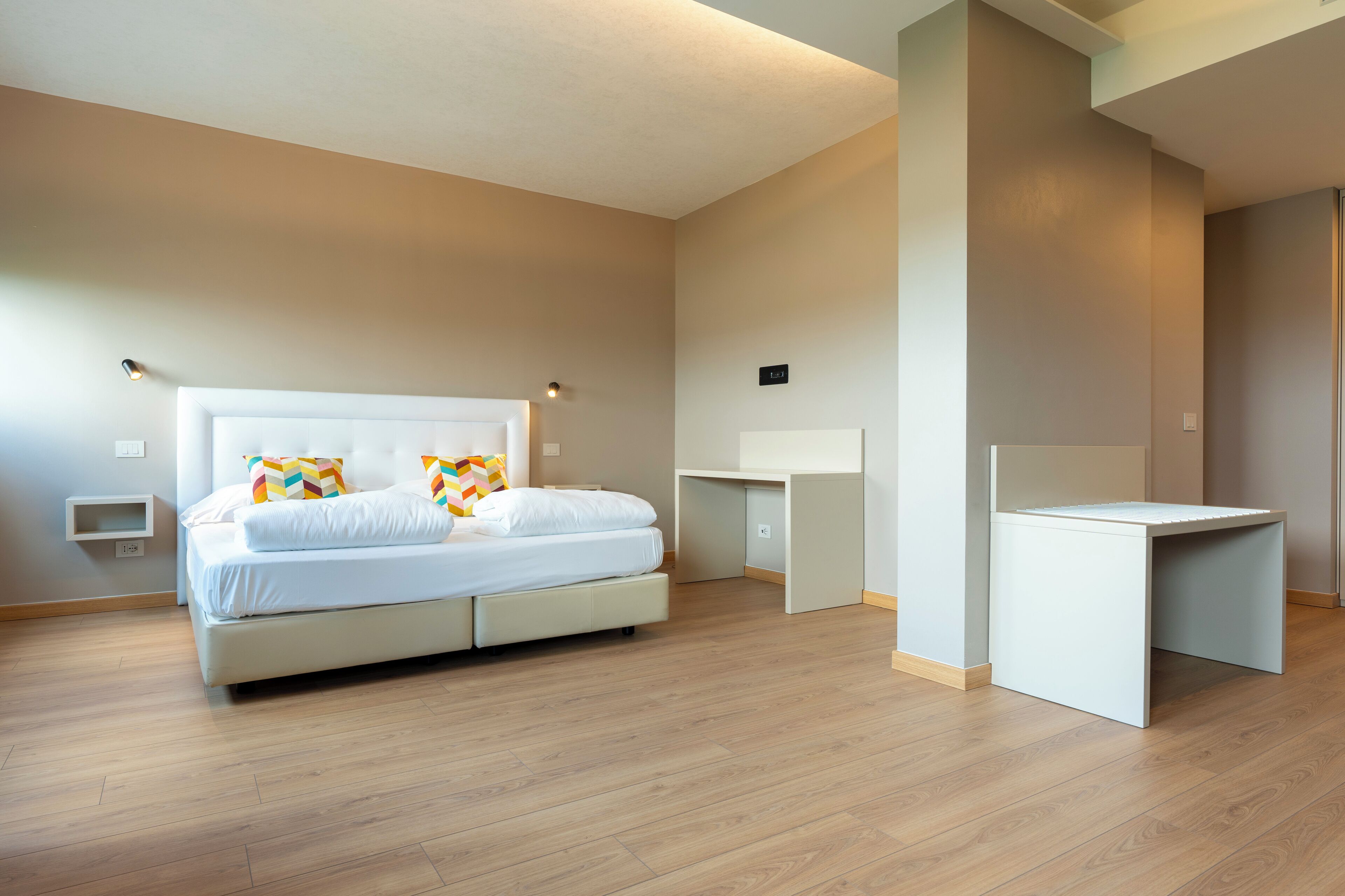 Una camera da letto moderna con un letto, comodini e una scrivania.