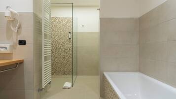 Un baño moderno con cabina de ducha, bañera y secador de pelo en la pared.