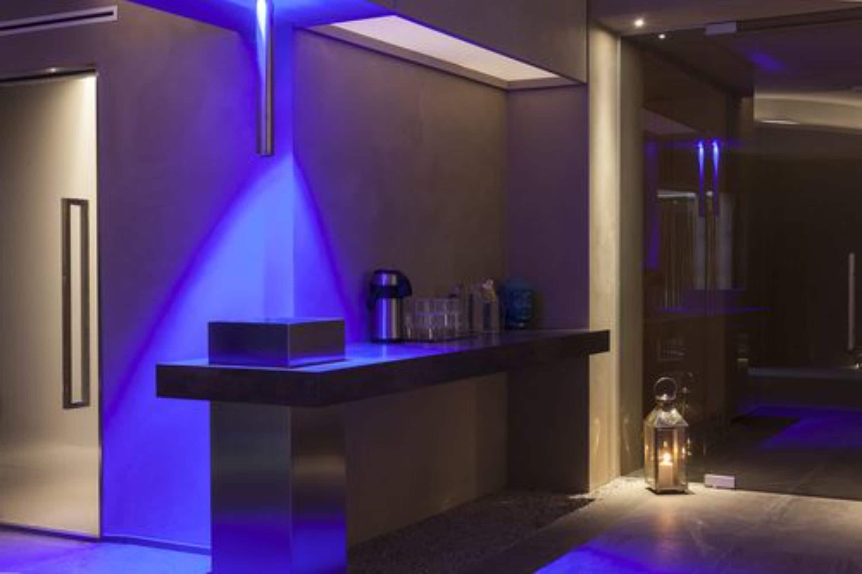 Eine moderne Hotelhalle mit einer Rezeption, einer Glastrennwand und einem kleinen Tisch mit einer Laterne.