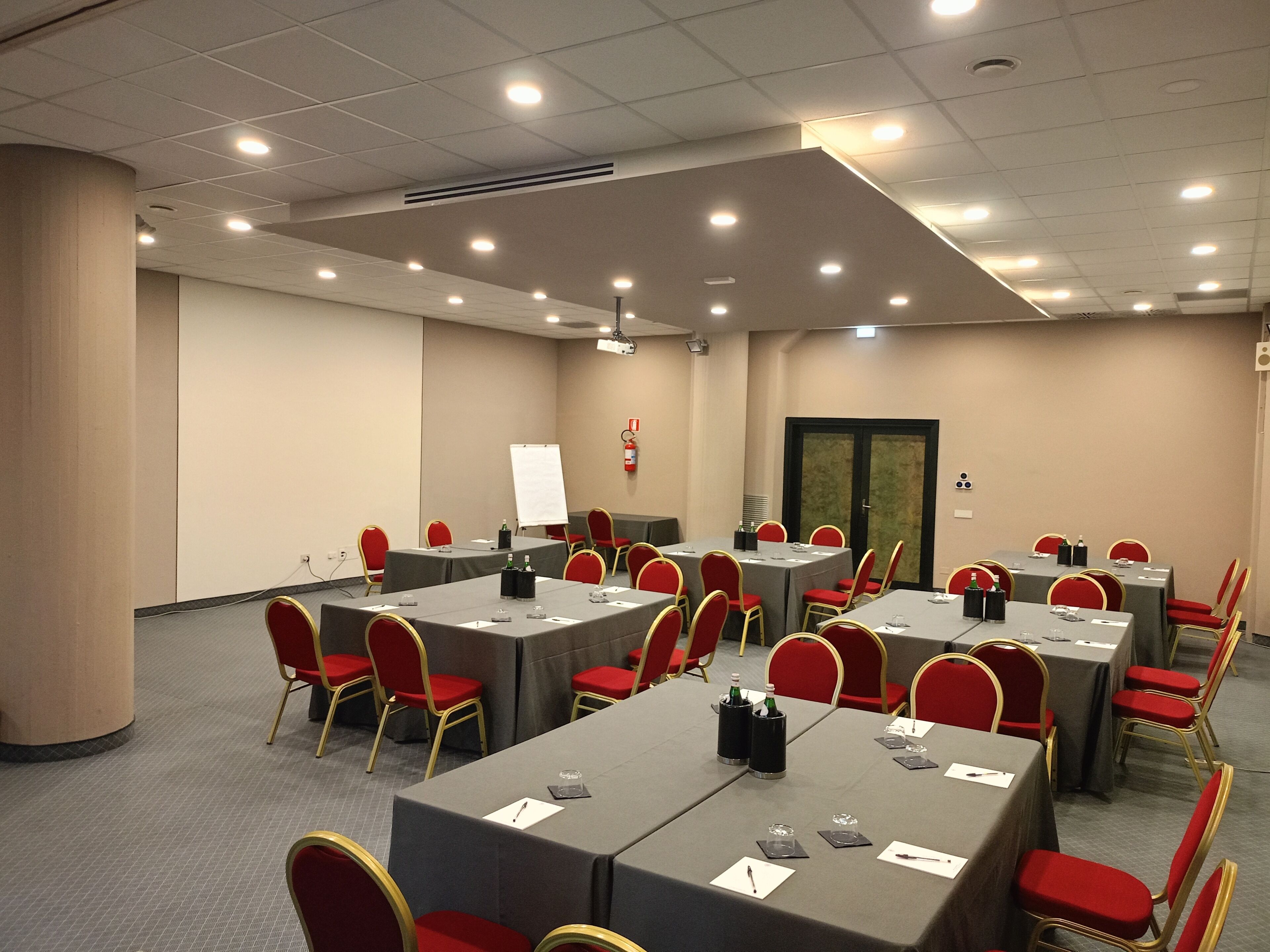 A conference room with multiple tables, red chairs, and a whiteboard.