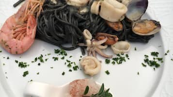 Un plato de pasta con mariscos, incluyendo camarones, calamares y almejas, decorado con hierbas.
