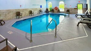En inomhuspool med fri sikt över poolområdet, inklusive sittplatserna vid poolkanten och poolens kant.