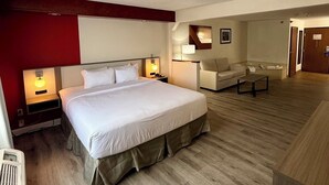 Ett hotellrum med en stor säng, sängbord, ett skrivbord, en stol och en spegel.