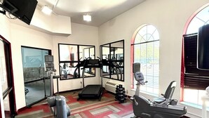 Ett gym med träningsutrustning, en tv och stora fönster.