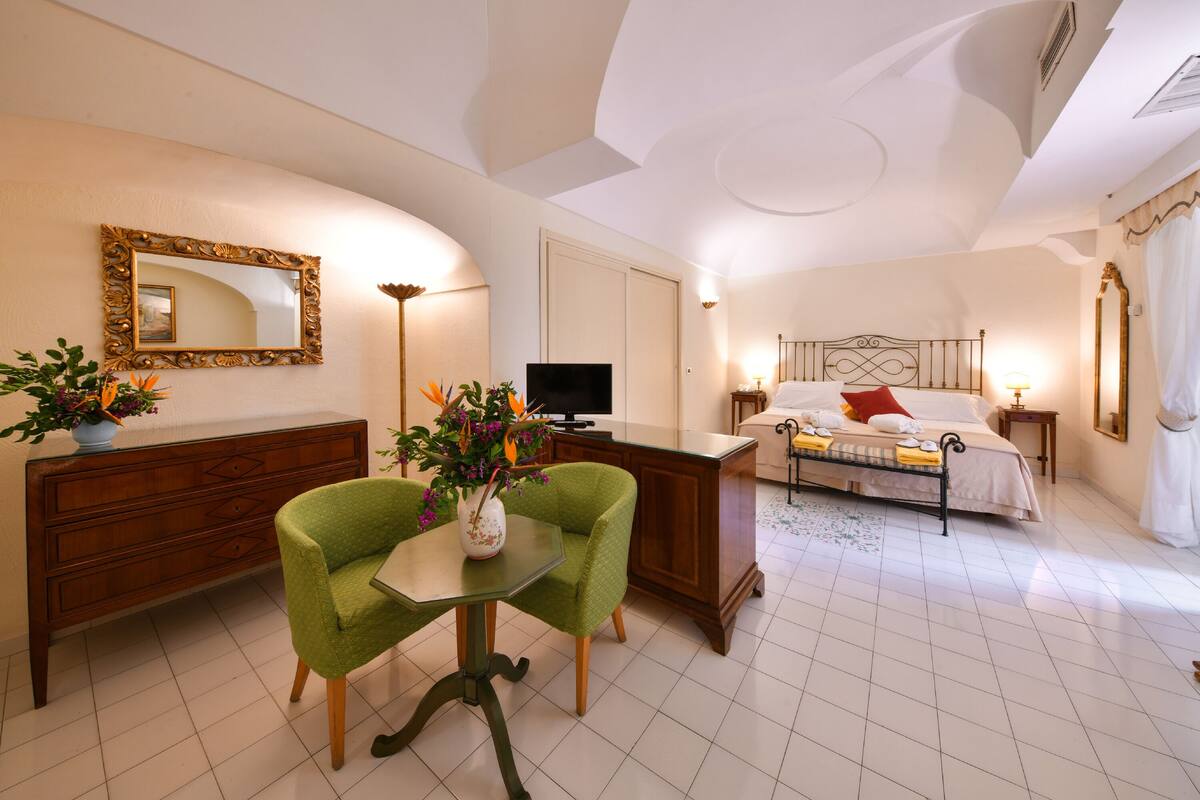 Een hotelkamer met een bed, een bureau, een stoel, een televisie en een grote spiegel.