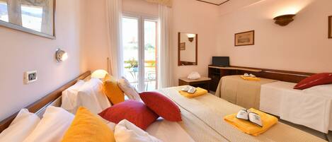 Ein Hotelzimmer mit zwei Betten, einem Balkon, einem Schreibtisch mit Stuhl und einem Fernseher.