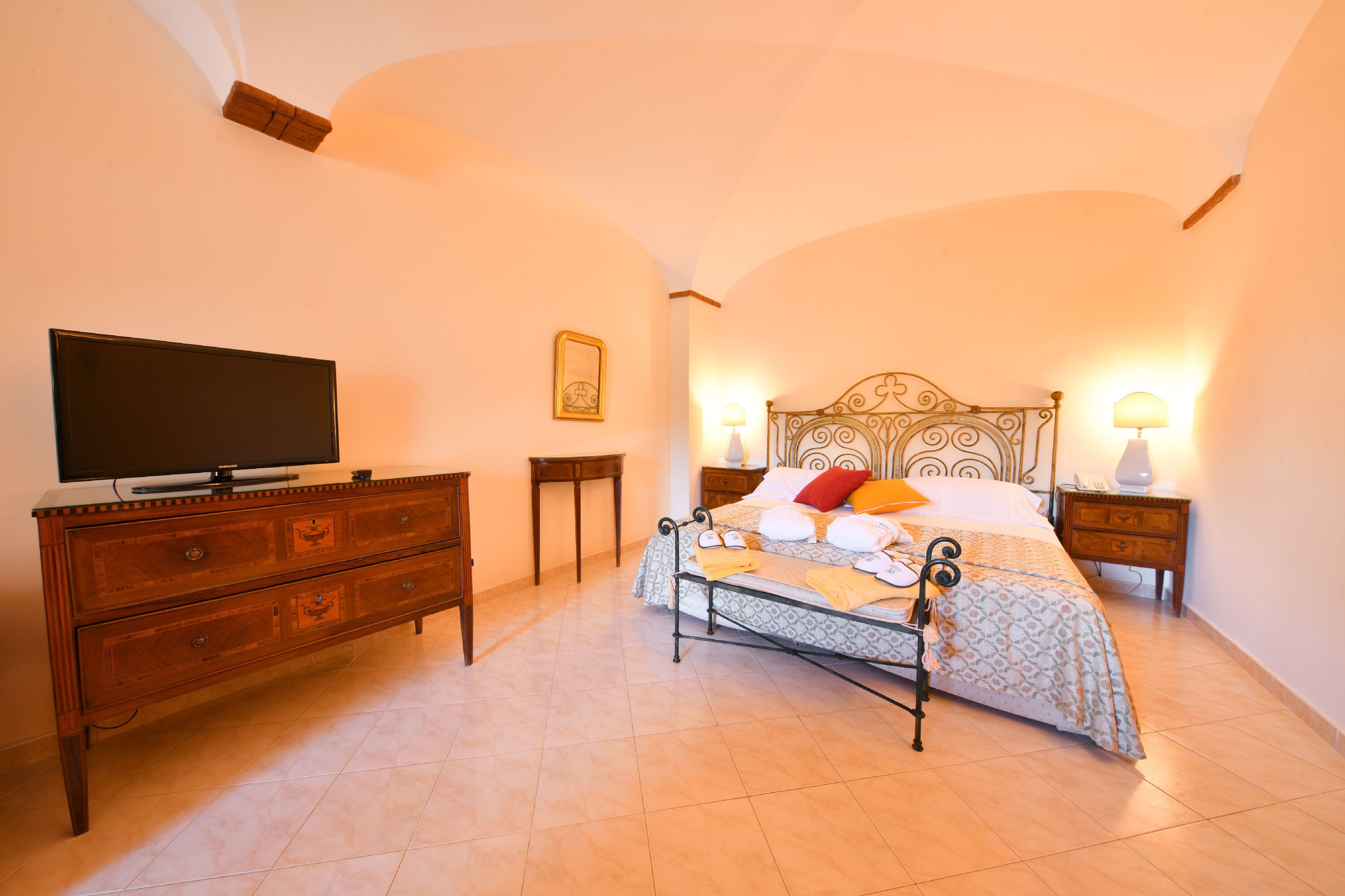 Un dormitorio con una cama, un aparador, un televisor y dos lámparas de noche.