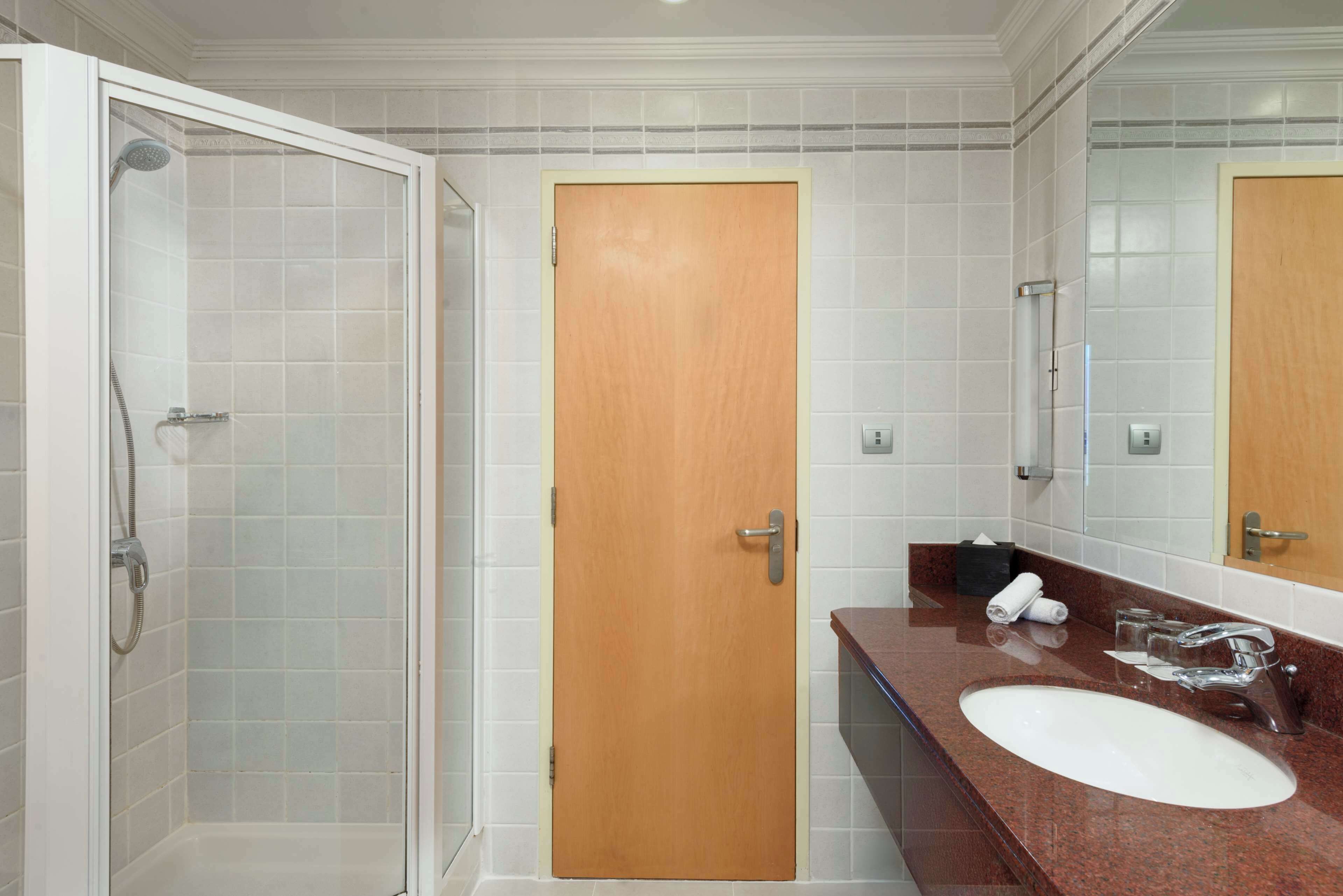 A bathroom with a shower, a sink, and a wooden door.