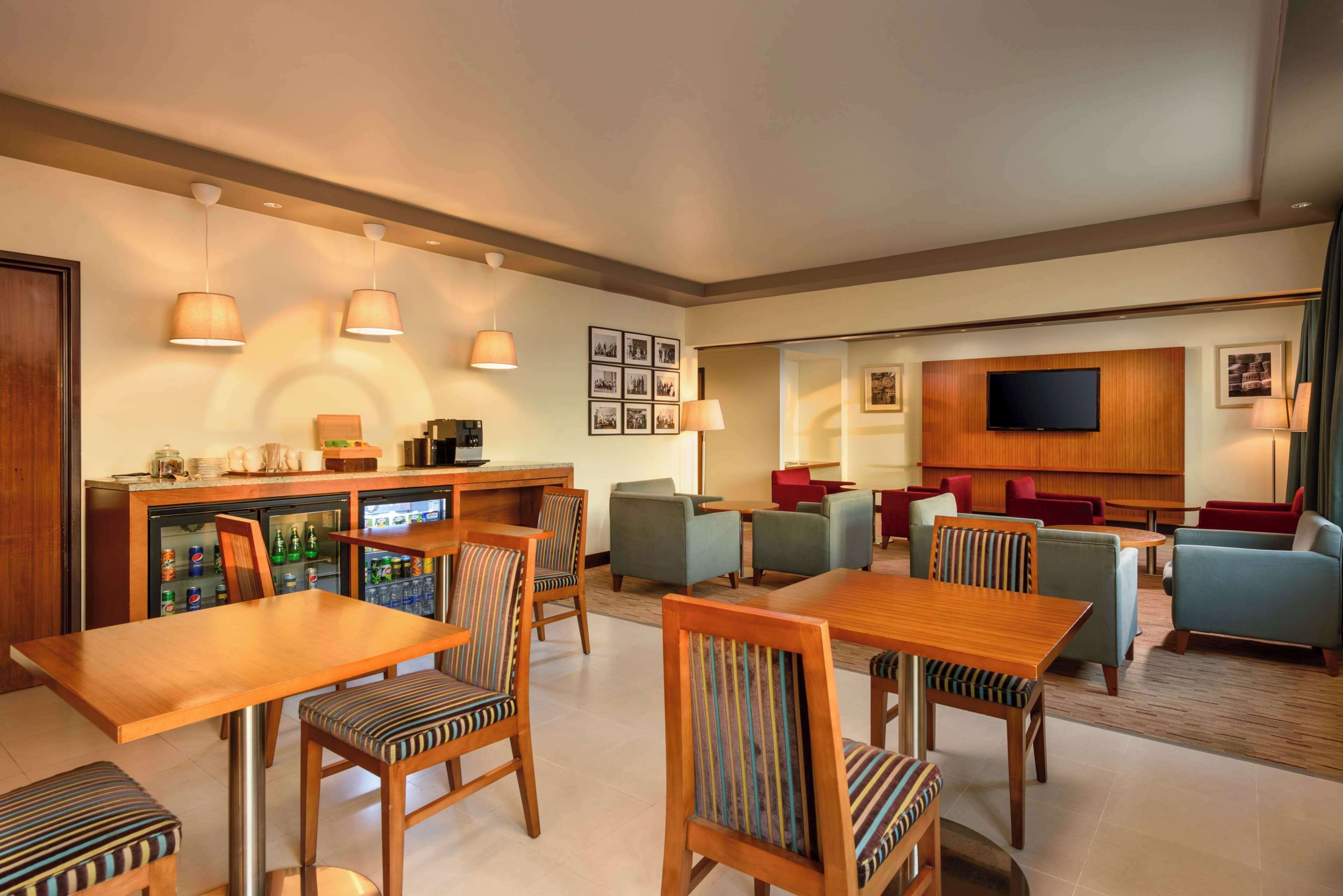 Eine moderne Hotelhalle mit Barbereich, Sitzgelegenheiten und einem an der Wand befestigten Flachbildfernseher.