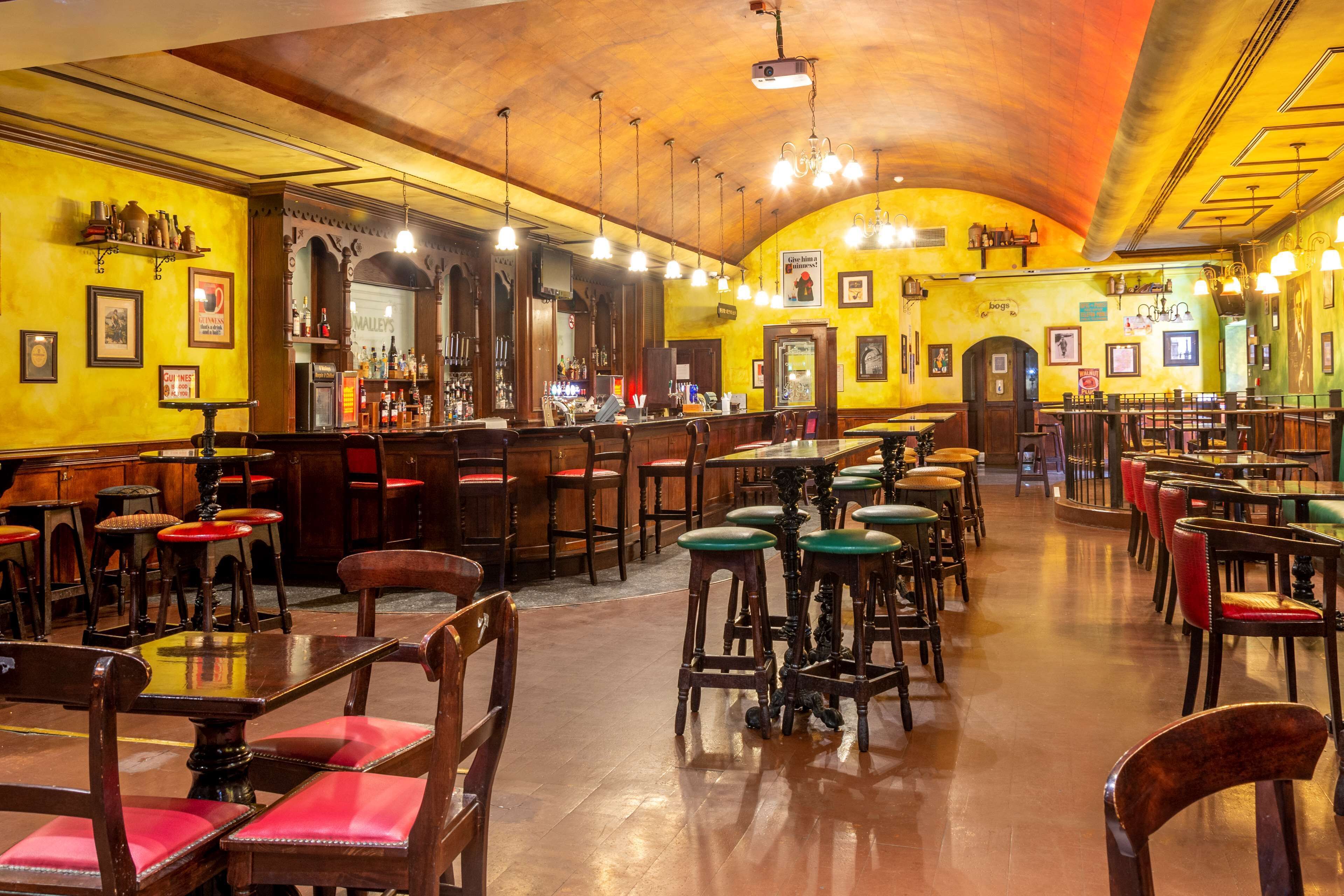 A spacious restaurant with high ceilings, wooden furniture, and a bar area.