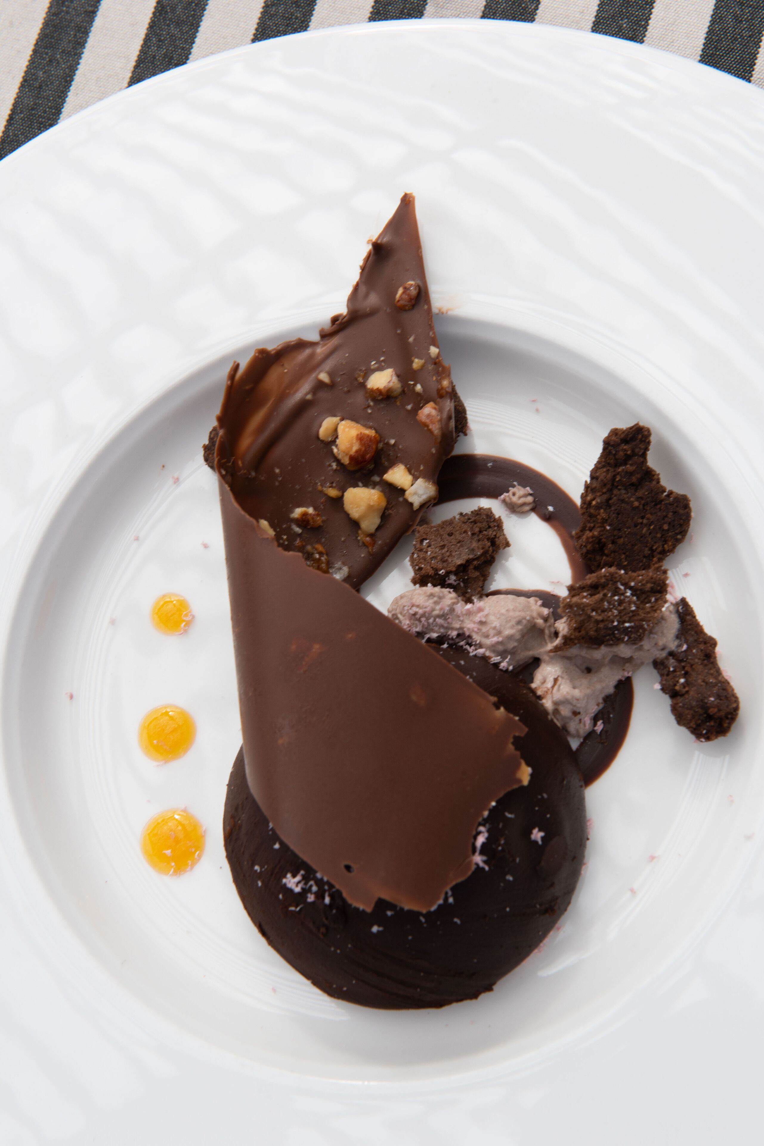 A dessert on a white plate with chocolate and ice cream.