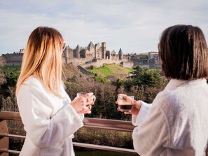 Dos personas contemplan un castillo histórico con vistas al paisaje circundante.