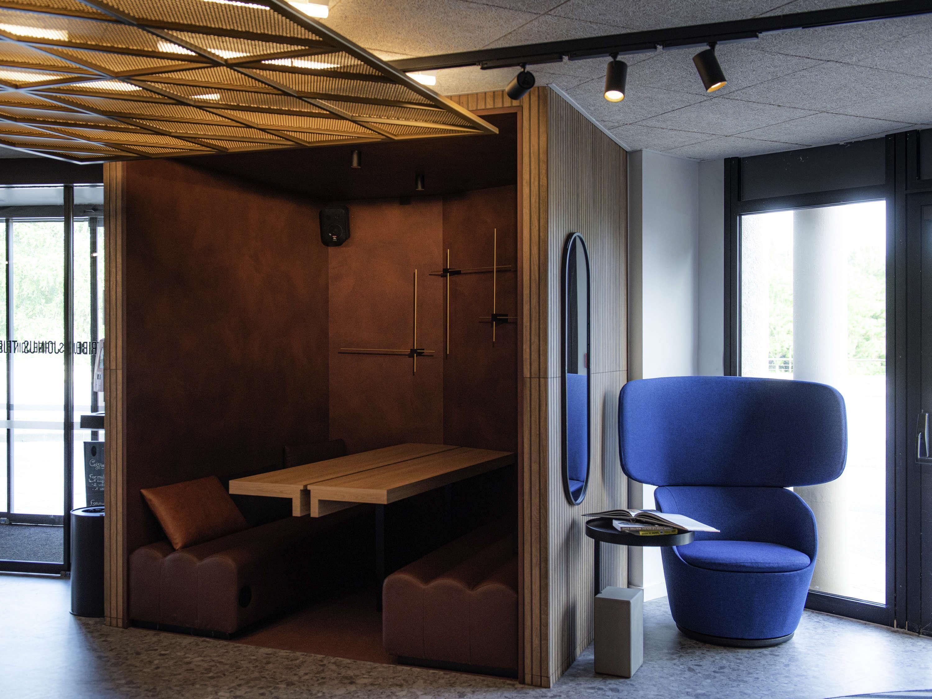 A modern room with a wooden table, blue chair, and a unique ceiling design.