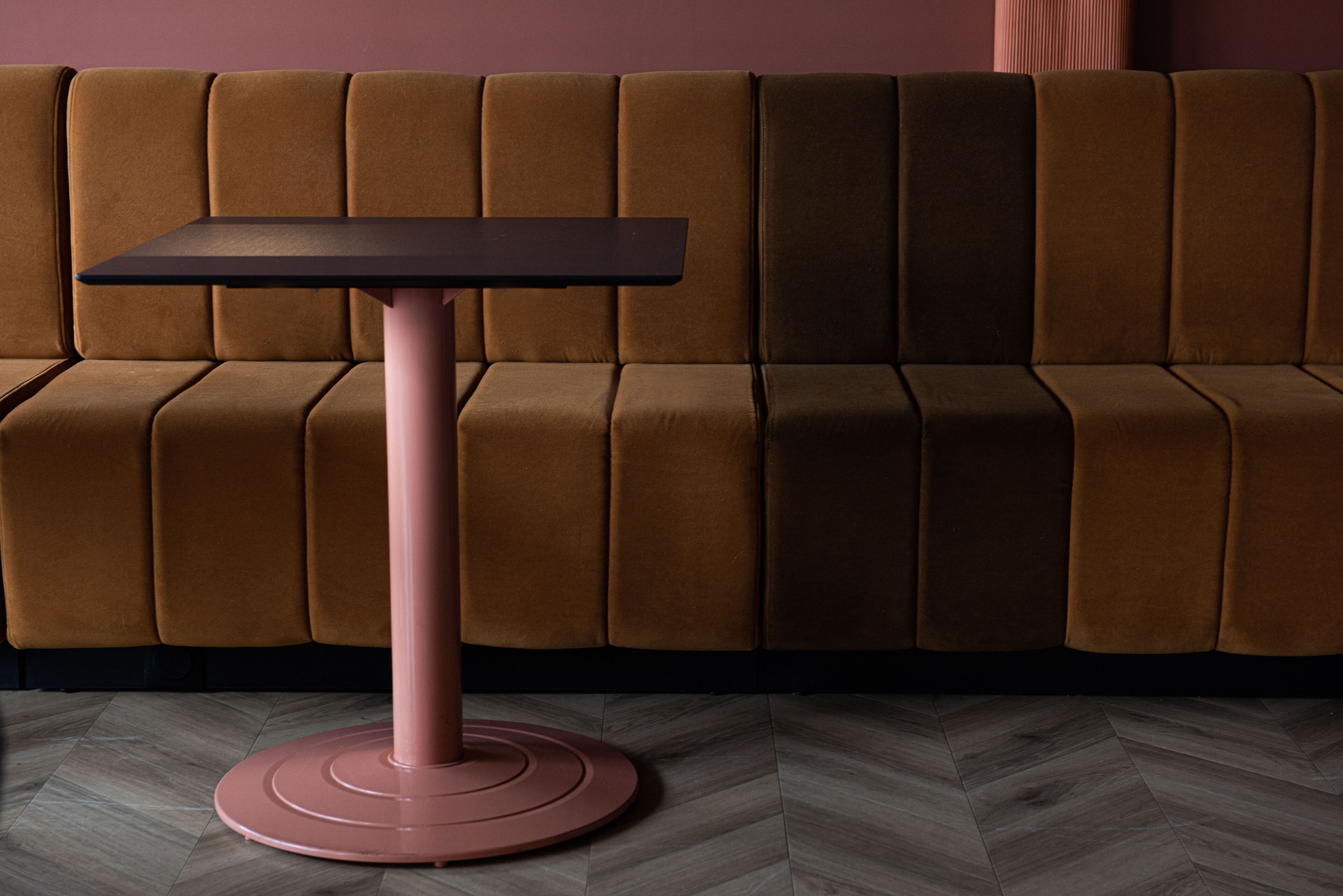 Una habitación moderna con un sofá marrón y una mesa rosa.