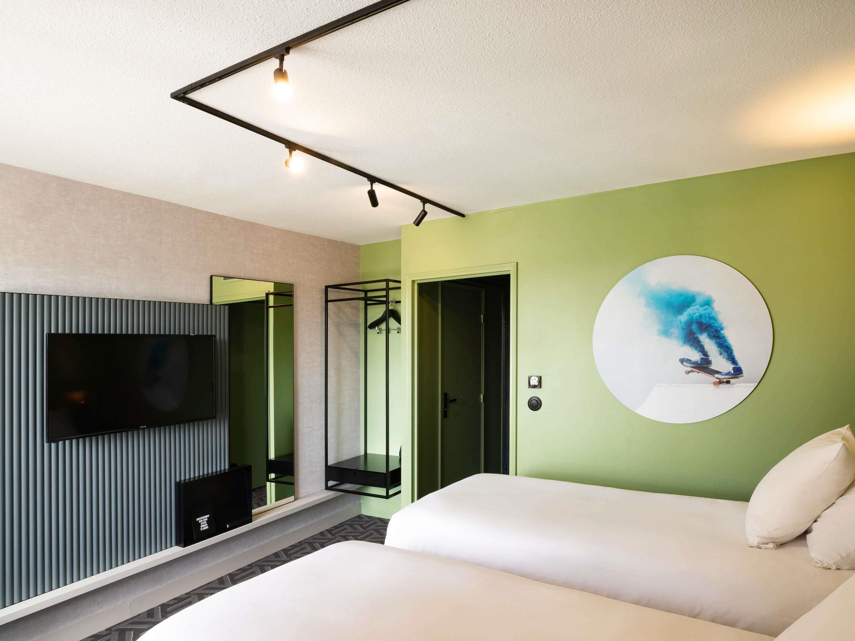Ein Hotelzimmer mit einem Bett, einem Fernseher, einem Spiegel und einer Tür.