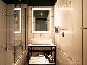 A modern bathroom with a glass-enclosed shower, a white sink, and a mirror above it. - Tribe Carcassonne (Carcassonne)