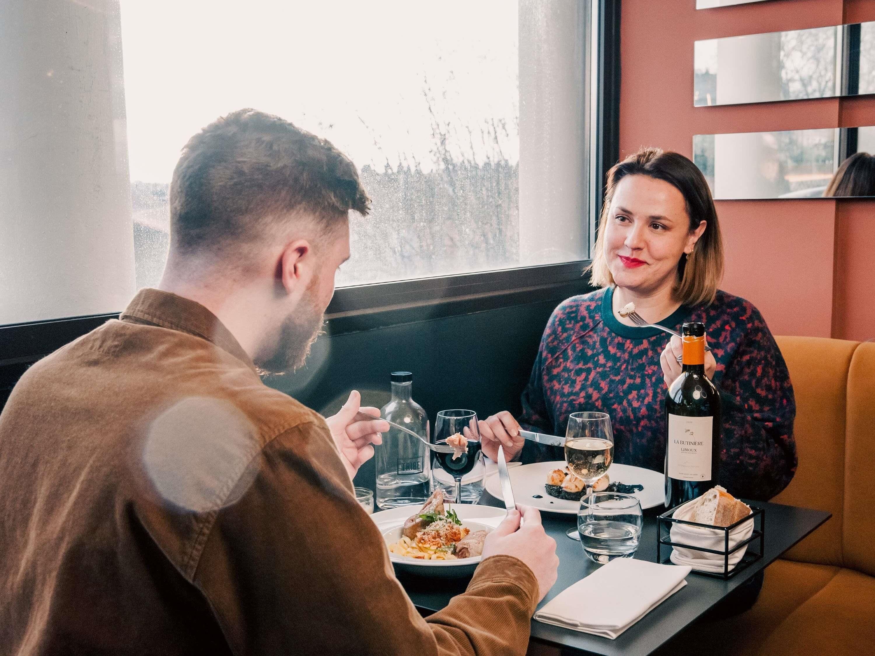 Une table à manger avec des assiettes remplies de nourriture, des verres et une bouteille de vin.