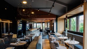 A modern restaurant with a long counter, seating area, and large windows. - Tribe Carcassonne (Carcassonne)