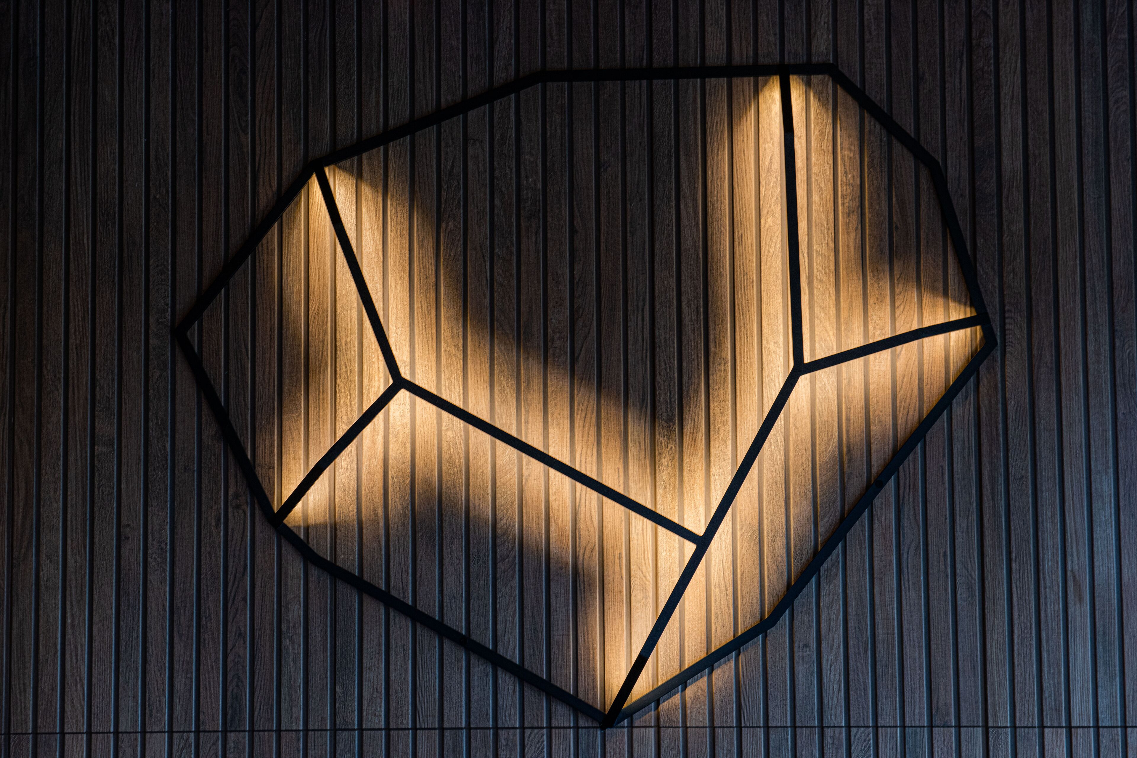 Eine geometrische Leuchte mit wabenartigem Design an einer Holzwand.