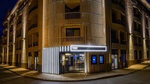 A modern hotel with a curved facade, multiple balconies, and a prominent entrance with a digital display. - Tribe Carcassonne (Carcassonne)