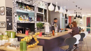 Una zona de bar con mostrador, estantes llenos de botellas, una máquina de café y una decoración de frutas.