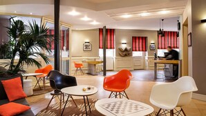Un espacio lounge moderno con sofá, sillas, una mesa de centro y una planta grande.