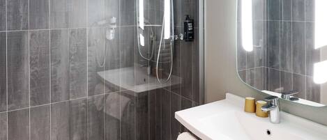A modern bathroom with a shower, a sink, a mirror, and a towel rack.