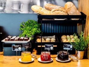 A buffet with various food items, including bread, pastries, and jars of jam.