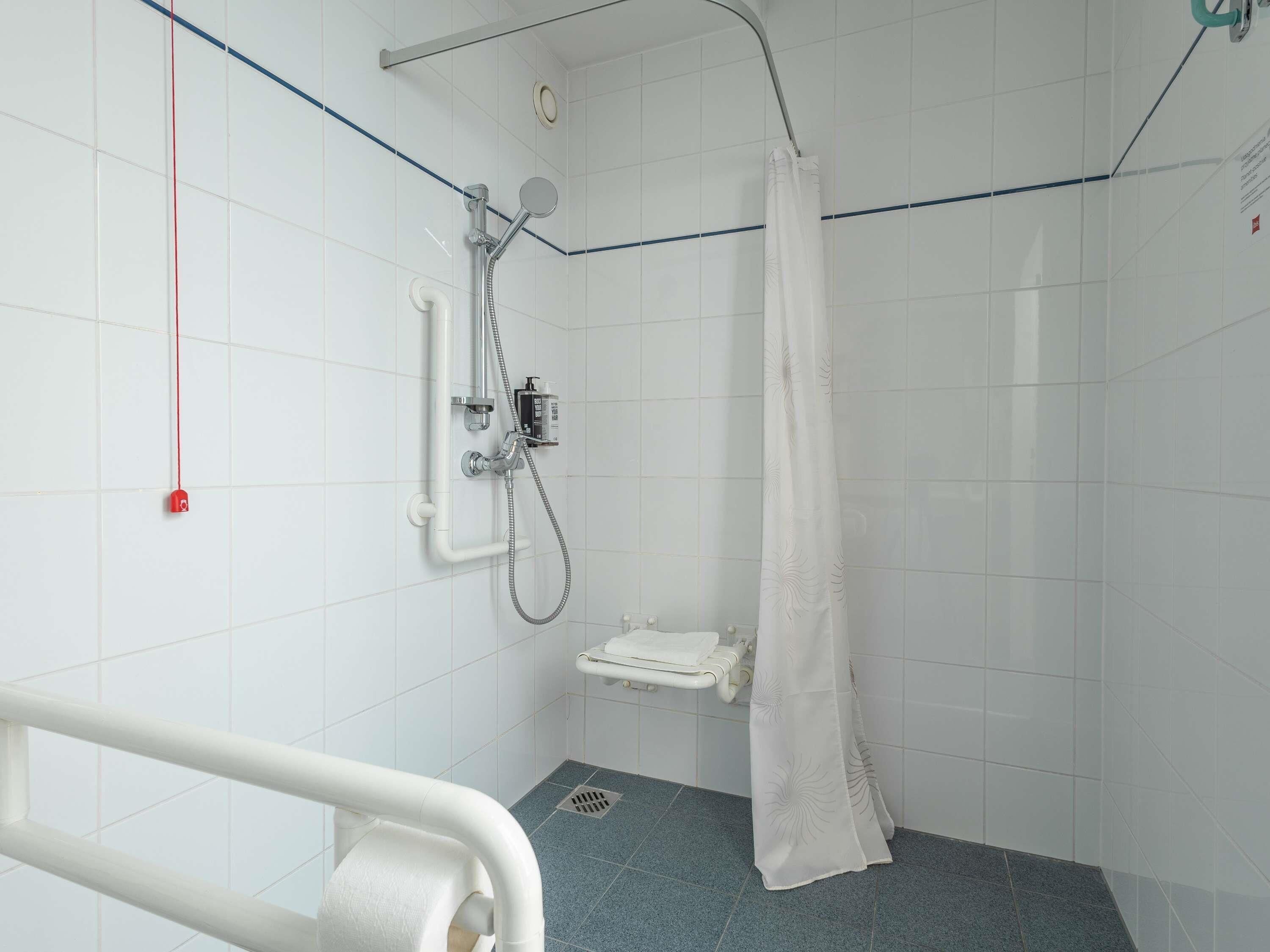 A shower area with a handheld showerhead, a towel rack, and a shower curtain.