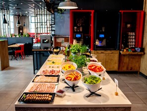 Een buffet tafel met diverse gerechten en een modern interieur met rode accenten en hangende lampen.