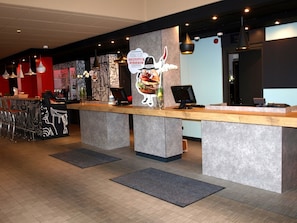A modern reception area with a counter, seating, and a large wall mural.