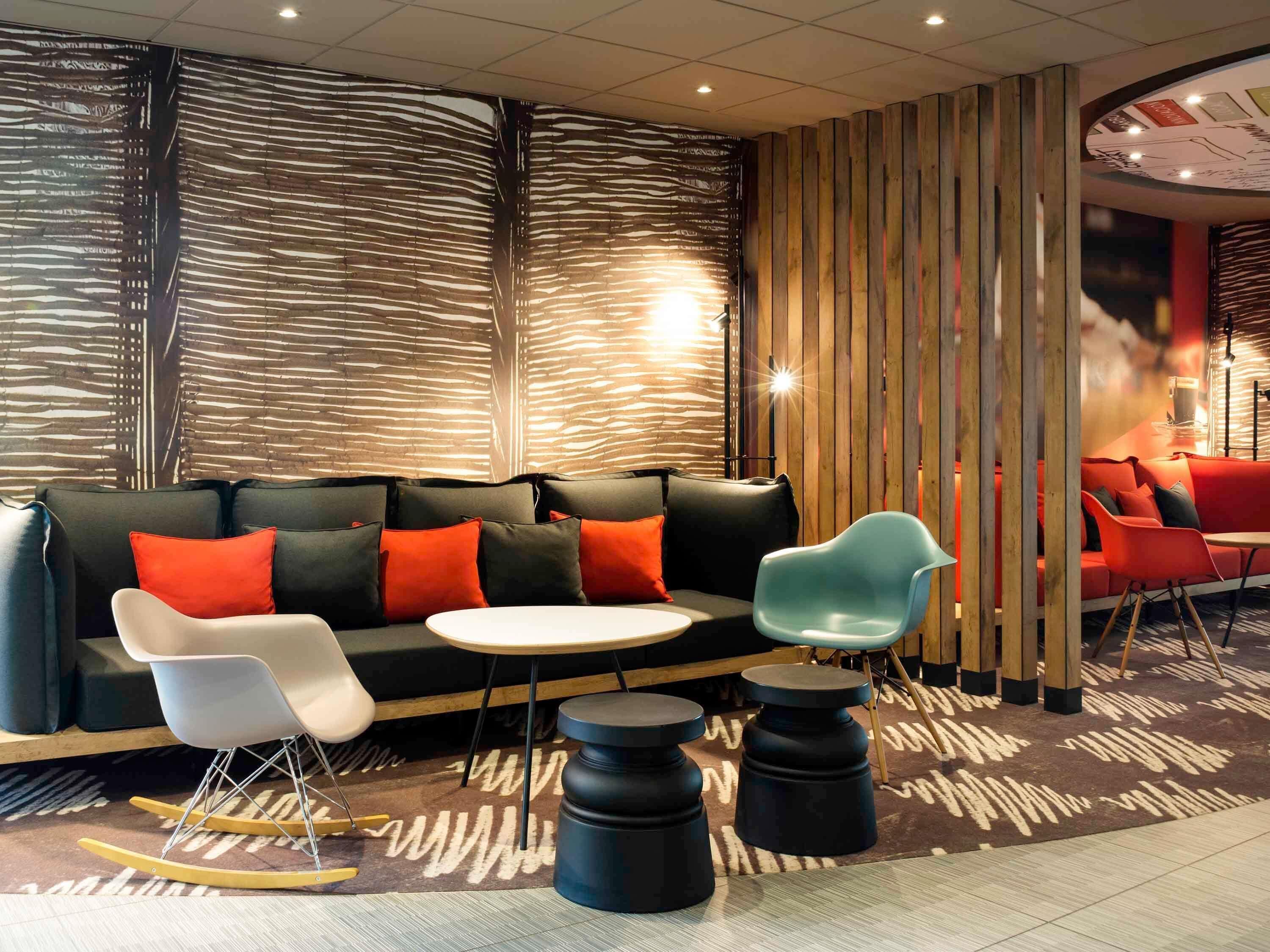 A modern lounge area with a sofa, chairs, a small table, and a patterned floor.