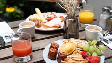 A breakfast setting with a plate of food, a glass of orange juice, and a cup of coffee on a wooden table.