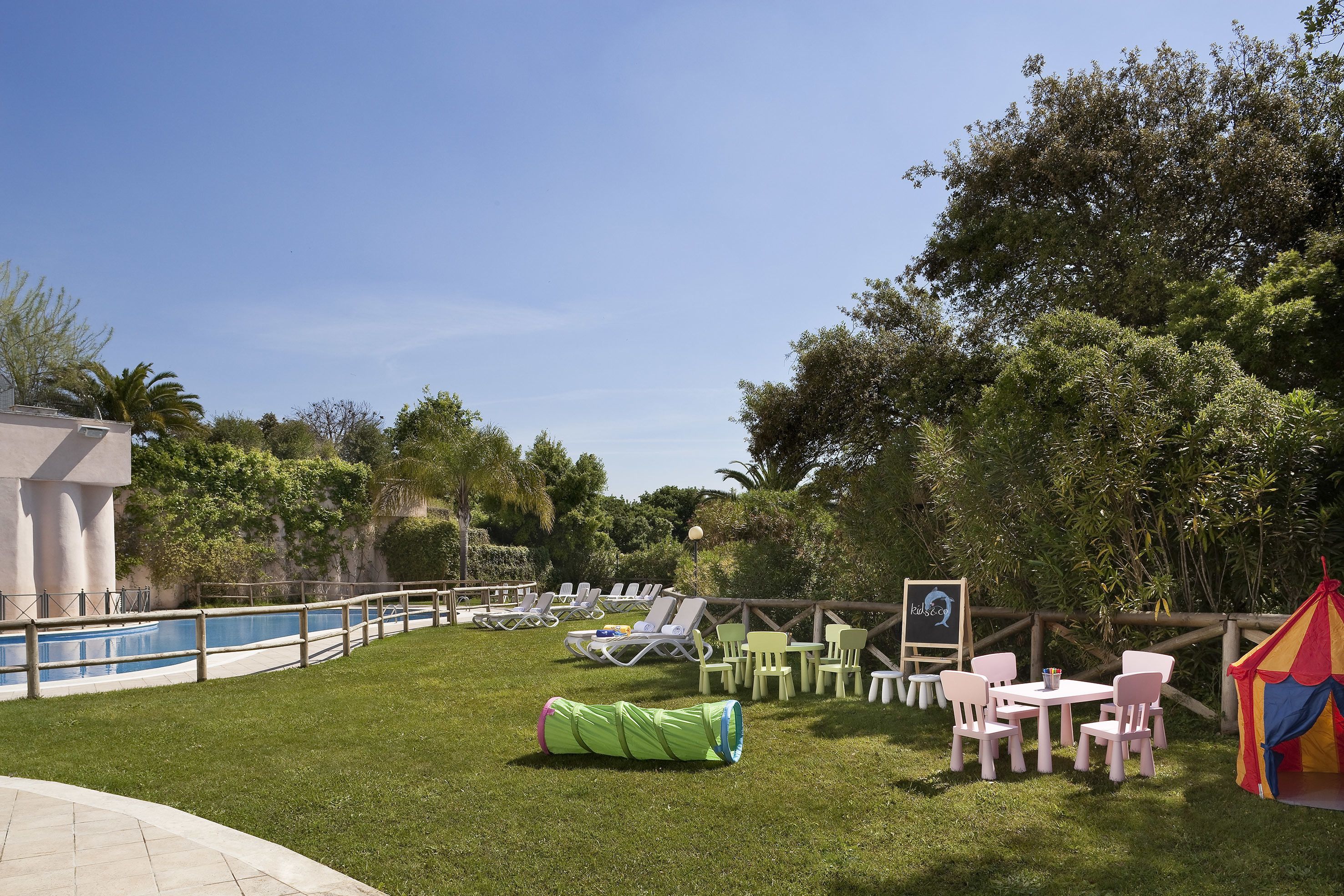 Un área junto a la piscina con sillones de descanso, una mesita y una carpa.