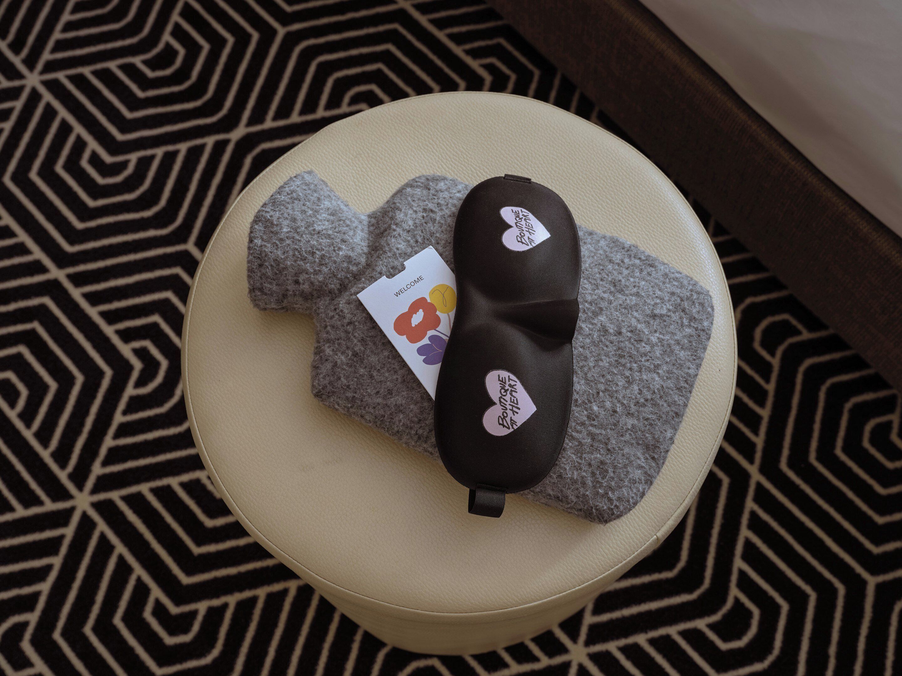 A round ottoman with a black and white tag, a grey cushion, and a patterned rug.