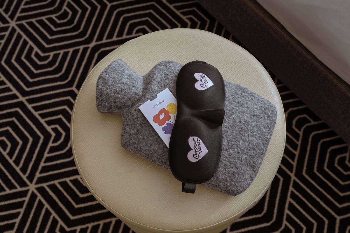 A round ottoman with a black and white tag, a grey cushion, and a patterned rug.