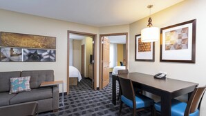 A hotel room with a sofa, a small table, a dining table with chairs, and artwork on the walls. - Towneplace Suites by Marriott East Lansing (East Lansing)