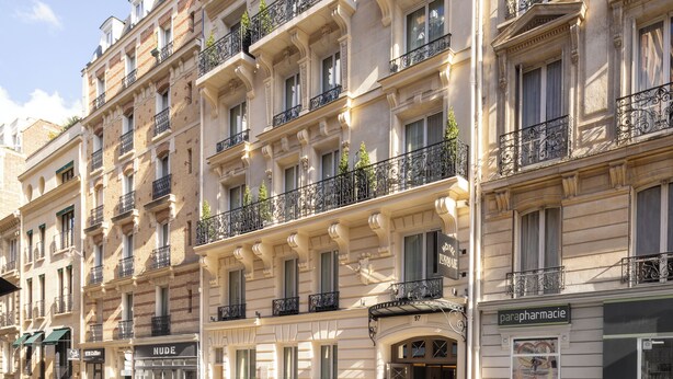 A multi-story building with ornate balconies, a pharmacy sign, and a store named 'NUDE'. - Hôtel L'Ormaie & Spa (Paris)