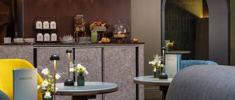A modern bar area with a marble countertop, bar stools, and a menu stand.
