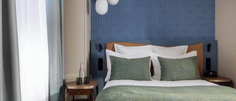 A hotel room with a bed, a nightstand, a lamp, and a chair.