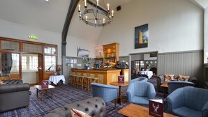 A hotel lobby with a bar area, seating arrangements, and a chandelier. - The Stirling Highland Hotel (Stirling)